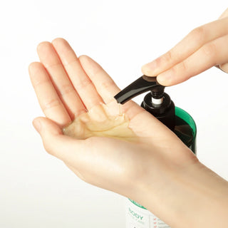 A close-up of SOMEBYMI’s AHA BHA PHA 30 Days Miracle Body Cleanser being dispensed onto the model's hand. The product shows a smooth, clear texture.