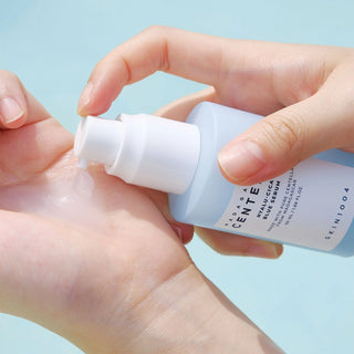 A close-up of SKIN1004's Madagascar Centella Hyalu-Cica Blue Serum being dispensed onto the model's hand, showcasing its light gel-type texture.