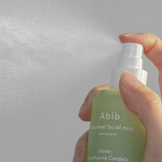 A close-up of Abib's Heartleaf Facial Mist Calming Spray in use reveals a micro-fine mist being dispensed.