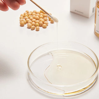 A Q-tip dipped in mixsoon's Bean Essence displays the serum dripping and revealing its thicker texture.
