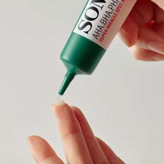 A close-up of SOMEBYMI's AHA BHA PHA 14 Days Super Miracle Spot All Kill Cream being dispensed onto a finger shows its transparent gel texture.