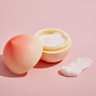 TONYMOLY's Peach Hand Cream is opened with a small amount smeared to show its thick, creamy texture.