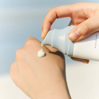 Close-up of SKIN1004's Madagascar Centella Hyalu-Cica Water-Fit Sun Serum SPF 50+ PA++++ being dispensed onto the model’s hand, showing its light texture.