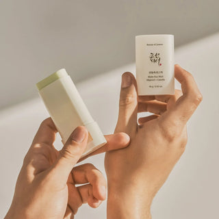 Close-up of a model’s hand holding Beauty of Joseon’s Matte Sun Stick Mugwort + Camellia SPF 50+ PA++++ with the cap off, showing the stick’s appearance.